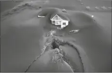  ?? EMILIO MORENATTI/AP ?? A FISSURE IS SEEN NEXT TO A HOUSE covered with ash on the Canary island of La Palma, Spain, Wednesday.