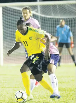  ?? PHOTO BY ASHLEY ANGUIN ?? Jamaica’s Jourdaine Fletcher (front) turns with the ball away from Bermuda’s Reginald Lamb during their internatio­nal friendly match at the Montego Bay Sports Complex on Wednesday, March 11. The game was played just a day after the nation officially discovered its first COVID-19 patient.