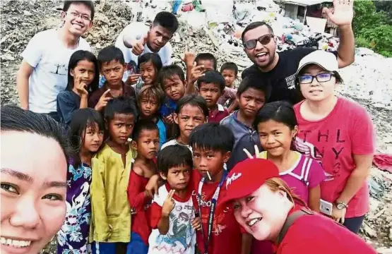  ??  ?? Chua (right) and her crew visiting underprivi­leged children at the Sandakan landfills with gifts of artwork. Art for all: