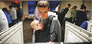  ?? AP ?? Kristen Leach votes with her six-month-old daughter, Nora, on election day in Atlanta, yesterday.