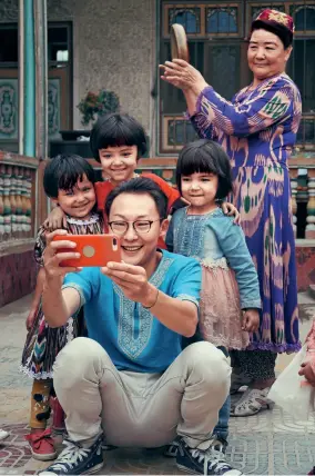  ??  ?? Wang Jiangjiang se photograph­ie avec des enfants.