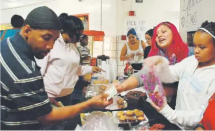  ?? Nicholas Garcia, Chalkbeat Colorado ?? Eymi Velazquez, second from right, takes money from a Gilpin Montessori parent at a bake sale in December. Velazquez helped raise money for her classroom’s pets.