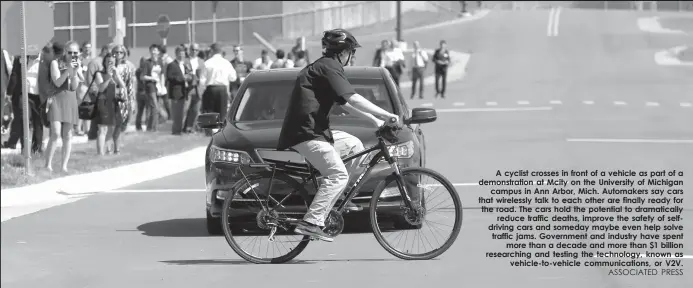  ?? ASSOCIATED PRESS ?? A cyclist crosses in front of a vehicle as part of a demonstrat­ion at Mcity on the University of Michigan
campus in Ann Arbor, Mich. Automakers say cars that wirelessly talk to each other are finally ready for the road. The cars hold the potential to...