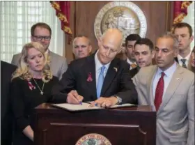  ?? MARK WALLHEISER — THE ASSOCIATED PRESS ?? Florida Gov. Rick Scott signs the Marjory Stoneman Douglas Public Safety Act in the governor’s office at the Florida State Capitol in Tallahasse­e, Fla., Friday. Scott is flanked by victims’ parents Gena Hoyer, left, Ryan Petty, second from left, Andrew...