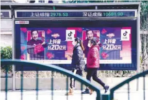  ??  ?? Women walk in front of an electronic board showing the Shanghai and Shenzhen stock indices in Shanghai, China, yesterday. – REUTERSPIX