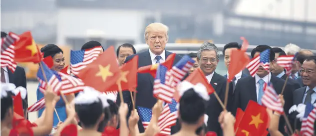  ??  ?? President Donald Trump watches as young girls wave U.S. and Vietnamese national flags before boarding Air Force One to depart to the Philippine­s, at the airport in Hanoi, Vietnam, Nov. 12.