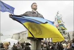 ?? MARKO DROBNJAKOV­IC/AP ?? A protester holding a Ukrainian flag in Kiev’s Independen­ce Square, the epicenter of the country’s current unrest.