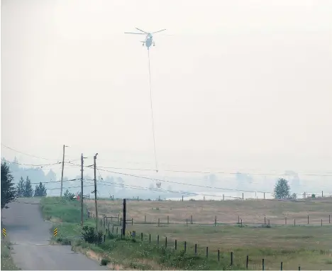  ?? DARRYL DYCK/THE CANADIAN PRESS ?? A bucket-carrying helicopter picks up water while battling the Gustafsen wildfire near 100 Mile House.