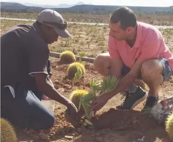  ??  ?? Netflorist MD Ryan Bacher plants an indigenous plant in the Mother Flag assisted by caretaker Attie Henricks.