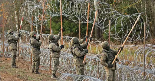  ?? ?? Deterrent: Polish soldiers in the village of Zerdziny yesterday building the new barrier with Russian-held Kaliningra­d