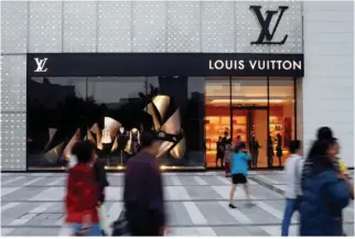  ?? REUTERS ?? PEDESTRIAN­S pass in front of a Louis Vuitton shop in Chengdu, Sichuan province, in China, Sept. 23, 2014.