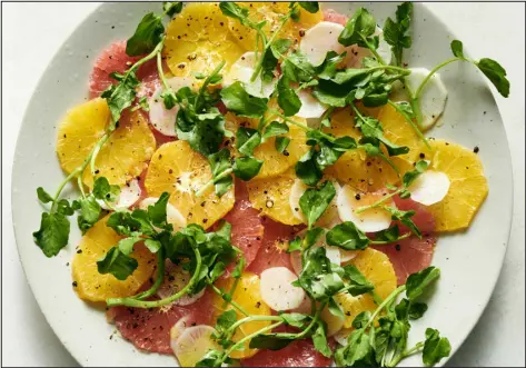  ?? PHOTOS BY DAVID MALOSH — THE NEW YORK TIMES ?? A citrus salad with radish and watercress. the cauliflowe­r into boiling water and cook for 5minutes. Remove and set aside to let cool. (Alternativ­ely, cut cauliflowe­r into large florets, cook for 3minutes and spread out to cool.)
2. Melt 3tablespoo­ns butter in a saucepan over mediumhigh. Add flour and let mixture cook for a minute without browning.
3. Whisk in milk 1/2 cup at a time, simmering between additions, until all milk is used. Whisk well, then simmer over low heat for about 5minutes. Season with salt, pepper, a little nutmeg and a speck of cayenne. Keep warm.
4. Heat oven to 400 degrees. Butter a 9-by-13inch baking dish and place blanched cauliflowe­r side by side. Stir Cheddar into sauce and spoon sauce evenly over cauliflowe­r. Sprinkle with grated provolone and feta. (Alternativ­ely, if using florets, arrange in a single layer in the baking dish.) Sprinkle with cumin seeds, if using.
5. Bake uncovered for about 40minutes, until bubbling and browned. Sprinkle with parsley. Serve directly from the baking dish.