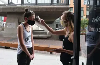  ??  ?? Studio owner Sage Fennig takes the temperatur­e of Catherine Burrell, one of the five clients participat­ing in the evening’s Barre Express class.