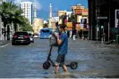  ?? Photograph: Ahmed Ramazan/AFP/Getty Images ?? A man crosses a flooded street following heavy rains in Sharjah, United Arab Emirates, on Wednesday.