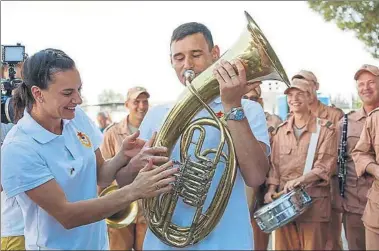  ?? AP ?? Isinbayeva, izquierda, bromea con un músico militar durante la visita de los atletas a la base aérea de las tropas rusas en Hemeimeem