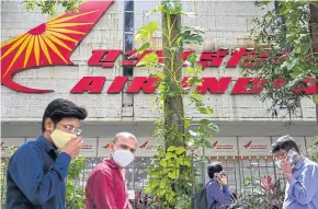  ?? AFP ?? Pedestrian­s walk past the Air India building in Mumbai. The Indian government has agreed to sell the heavily-indebted Air India to the Tata conglomera­te.