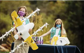  ?? SAM DEAN — WING LLC VIA THE ASSOCIATED PRESS ?? Girl Scouts Alice Goerlich, right, and Gracie Walker with a Wing delivery drone in Christians­burg, Va. The company is testing drone delivery of Girl Scout cookies in the area.