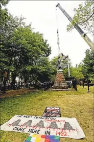  ?? Peter Hvizdak / Hearst Connecticu­t Media ?? Workers remove a statue of Christophe­r Columbus from its spot in Wooster Square Park in New Haven on Wednesday. On the ground is a sign reading ‘The most dangerous immigrants came here in 1492.’