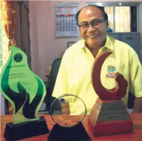  ??  ?? Masisit-Dacal Livelihood Cooperativ­e chief executive officer Froilan Pacris poses with three of the most cherished awards the co-op has received through its successful 29-year existence.