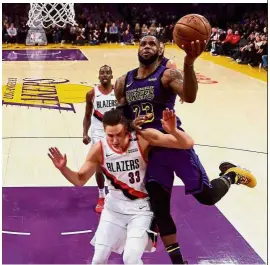  ??  ?? In it goes: LeBron James (right) of the Los Angeles Lakers scoring as he is fouled by Zach Collins of the Portland Trail Blazers during their NBA match at Staples Centre on Wednesday. — AFP
