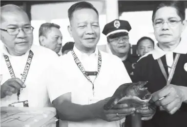  ?? (Ariel Fernandez) ?? BUREAU of Customs Commission­er Isidro Lapeña (center) holds one of the 123 Chinese Soft Shell turtles which was about to be smuggled out of the country but was foiled by authoritie­s. With Lapena are NAIA customs district collector Ramon Anquilan (left)...