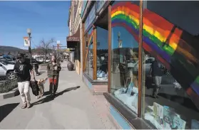  ?? Michael Macor / Special to The Chronicle ?? Truckee residents Tucker Adams (left) and Holly Shankland take their dog, Forest, on their morning walk to get coffee in downtown Truckee last month.