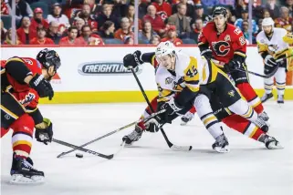  ??  ?? Penguins right wing Josh Archibald (45) reaches for the puck against the Flames during the third period at Scotiabank Saddledome on Monday night. (USA TODAY Sports)