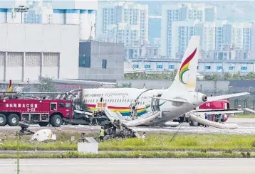  ?? LIU CHAN/XINHUA ?? The wreckage of a Chinese passenger jet that veered off a runway during an aborted takeoff and caught fire Thursday is examined by emergency workers. Chinese civil aviation officials said more than 30 people were injured when the Tibet Airlines jet, with 122 people on board, left the runway at Chongqing Jiangbei Internatio­nal Airport in Chongqing.