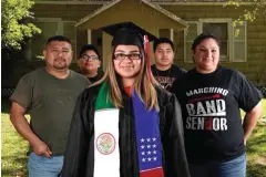  ?? Associated Press ?? ■ Maria Mendoza, center, wears her graduation cap and gown May 11 as she poses for a photograph with her family, from left, father Tomas Ahuja, brothers Joel and Emmanuel and mother Karina outside their home in Port Arthur, Texas.