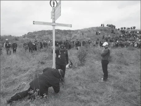  ?? The Associated Press ?? EVERYWHERE A SIGN: Rory McIlroy waits for a sign to be moved so he can play his shot in the rough on No. 15 during the second round of the British Open Friday at Royal Birkdale in Southport, England.