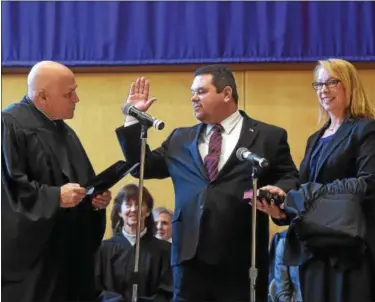  ?? PETE BANNAN — DIGITAL FIRST MEDIA ?? Newly eleced John Hipple of North Coventry is sworn as a district judge by Judge James V. DeAngelo at ceremonies held at West Chester University Sykes ballroom Wednesday. Holding the Bible is his wife Carrie Hipple.