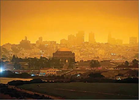  ?? ERIC RISBERG / AP ?? At 11:18 a.m. Sept. 9, a dark orange sky caused by heavy smoke from wildfires is seen above Crissy Field in San Francisco. Fires that scorched huge swaths of the West Coast churned out massive plumes of choking smoke that blanketed millions of people with hazardous pollution that spiked emergency room visits and that experts say could continue generating health problems for years. An Associated Press analysis of air quality data shows 5.2 million people in five states were hit with hazardous levels of pollution for at least a day.