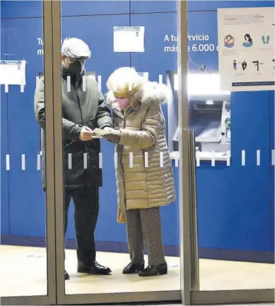  ?? Jaime Galindo ?? Una parella consulta la llibreta d’estalvis en una sucursal bancària.