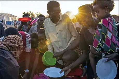  ?? NARIMAN EL-MOFTY — THE ASSOCIATED PRESS ?? Tigray refugees who fled the conflict in Ethiopia’s Tigray region, wait to get cooked rice served by Sudanese local volunteers at Um Rakuba refugee camp in Qadarif, eastern Sudan, Monday, Nov. 23, 2020. Ethiopia’s government is again warning residents of the besieged capital of the embattled Tigray region as the clock ticks on a 72-hour ultimatum before a military assault, saying “anything can happen.”