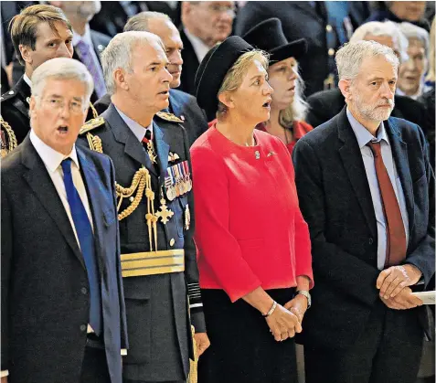  ??  ?? Defence Secretary Michael Fallon, left, is in good voice but Labour leader Jeremy Corbyn remains silent during the national anthem at a service to mark the Battle of Britain