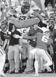  ?? [PHOTO BY SARAH PHIPPS, THE OKLAHOMAN] ?? Oklahoma State junior Tyron Johnson (13) leaps over Oklahoma’s Tre Brown during the Bedlam game in November. Johnson announced Monday that he’s leaving OSU early for the NFL.