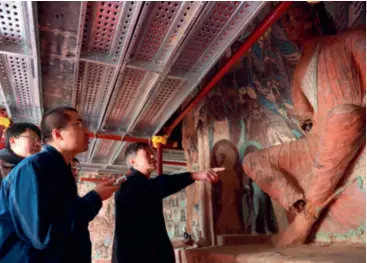  ?? ?? Su Bomin right) checks the restoratio­n of murals in Gansu Province, on February 23 cave in the Mogao Grottoes, Dunhuang,