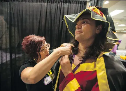  ?? LIAM RICHARDS ?? Loni Askwith, who works at a cosplay repair booth, helps reinforce some sewing on the cape of Robert Elash, dressed as Megumin from KonoSuba, at the Ganbatte Convention at TCU Place on Saturday.