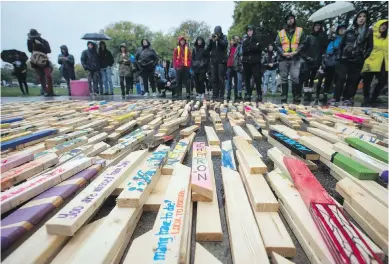  ?? DARRYL DYCK, THE CANADIAN PRESS ?? People listen to speeches as 2,224 wooden stakes representi­ng the number of confirmed overdose deaths in B.C. over the past three years are placed on the ground at Oppenheime­r Park in Vancouver on Friday. Many of the sticks are painted with names of...