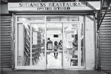  ?? ODED BALILTY/AP 2020 ?? A Sudanese migrant family in a closed restaurant in south Tel Aviv, Israel. Many of the migrants find it a struggle to make ends meet.