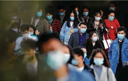  ?? Photos by Andy Wong / Associated Press ?? Commuters wearing face masks to help curb the spread of the coronaviru­s walk out from a subway station during the morning rush hour in Beijing on Tuesday.