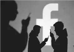  ?? — Reuters photo ?? Silhouette­s of mobile users are seen next to a screen projection of Facebook logo in this picture illustrati­on.