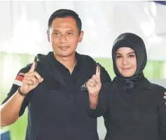  ??  ?? Agus Harimurti Yudhoyono (left), a candidate in the running to lead the Indonesian capital Jakarta, and his wife Annisa Pohan, show their fingers during an election for Jakarta’s governor in Jakarta, Indonesia. — Reuters photo