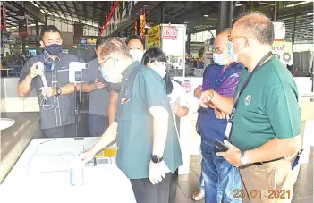  ??  ?? Uggah checks the customer’s logbook at the entrance to Bandar Riyal Market Food Court.