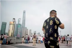  ??  ?? Dollari e yuan. Un cittadino cinese nel quartiere finanziari­o di Shanghai “vestito” di dollari