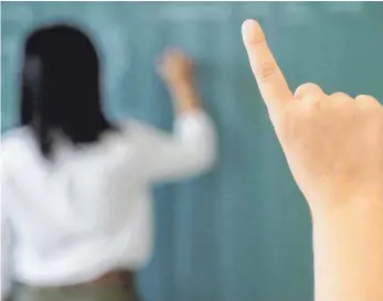  ?? FOTO: MARIJAN MURAT/DPA ?? Ein Schüler meldet sich, während die Lehrerin an die Tafel schreibt. In den Sommerferi­en finden in Baden-Württember­g sogenannte Lernbrücke­n statt. Dieses Angebot für schwächere Schüler soll helfen, Wissenslüc­ken aus der Corona-Zeit zu schließen.