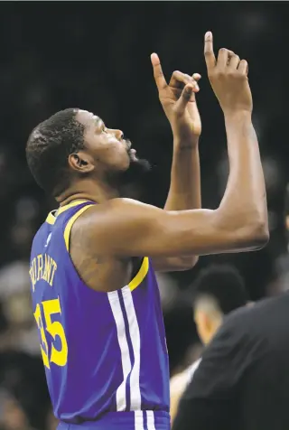  ?? Eric Gay / Associated Press ?? Kevin Durant points skyward as he walks onto the court before Game 3 in San Antonio, a day after the death of Spurs head coach Gregg Popovich’s wife, Erin.