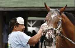  ?? TIMOTHY D. EASLEY ?? FILE - In this April 19, 2017 file photo, groom Cesar Abrego gives a bath to one of the horses being trained by Dale Romans following his morning workout at Churchill Downs in Louisville, Ky.