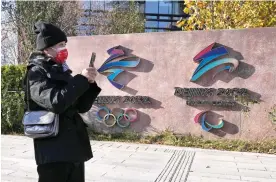  ?? AP Photo/Ng Han Guan ?? ■ A visitor to the Shougang Park walks past the logos Nov. 9 for the Beijing Winter Olympics and Paralympic­s in Beijing, China. China on Monday threatened to take “firm countermea­sures” if the U.S. proceeds with a diplomatic boycott of February’s Beijing Winter Olympic Games.