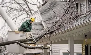  ?? Mandi Wright / Associated Press ?? An employee from Davey Tree cuts a large branch from a house in Pleasant Ridge, Mich., as ice caused widespread power outages.
